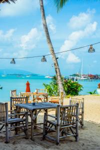 a table and chairs on a beach with the ocean at Secret Garden Beach Resort in Bangrak Beach