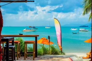 a table with chairs and umbrellas and the ocean at Secret Garden Beach Resort in Bangrak Beach