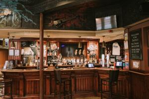 - un bar dans un pub avec des tabourets devant dans l'établissement The Saddle Inn, à Chester