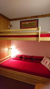 a bedroom with a red bed with two bunk beds at Bourg St Maurice les Arcs 1800 Les Lauzieres jolie vue, nature, espace, bien être, plaisir, paisible in Arc 1800