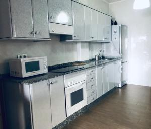 a kitchen with white cabinets and a microwave at Apartamento El Muellito in Playa Blanca +16 photos