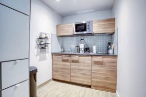 a kitchen with wooden cabinets and a microwave at Magnificent Studio Near The Canal De L'ourcq in Paris