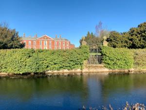 a large red brick building next to a body of water at Bosworth Hall Hotel & Spa in Market Bosworth
