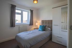 a bedroom with a bed with a blue pillow and a window at Vale House in Northfleet