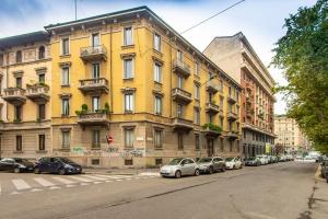 a yellow building with cars parked on a street at Elegante Casa Liberty in Milan