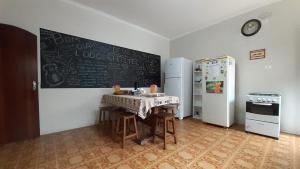 a kitchen with a table and two refrigerators and a chalkboard at Lodge Hostel Piracicaba in Piracicaba