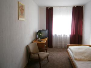 a hotel room with a bed and a tv and a chair at Hotel Strauss in Waldbronn