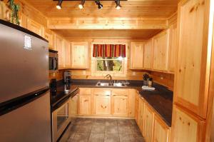 La cuisine est équipée de placards en bois, d'un évier et d'un réfrigérateur. dans l'établissement #2903 Abundantly Blessed, à Pigeon Forge