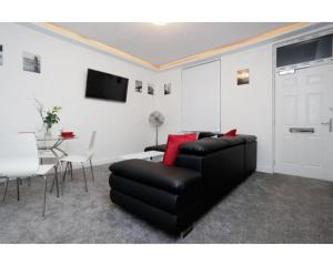 a living room with a black leather couch and a table at CARTER HOUSE APARTMENTS.....6 beds in 3 bedrooms in Leeds