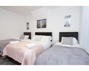 two beds in a room with white walls at CARTER HOUSE APARTMENTS.....6 beds in 3 bedrooms in Leeds