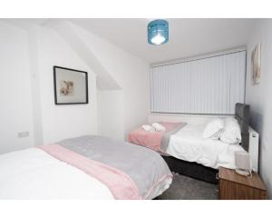 two beds in a bedroom with white walls at CARTER HOUSE APARTMENTS.....6 beds in 3 bedrooms in Leeds