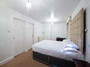 a white bedroom with a large bed and a lamp at George Hotel, Burslem, Stoke-on-Trent in Stoke on Trent
