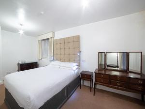 1 dormitorio con cama, tocador y espejo en George Hotel, Burslem, Stoke-on-Trent, en Stoke on Trent