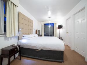 Un dormitorio con una gran cama blanca y una ventana en George Hotel, Burslem, Stoke-on-Trent, en Stoke on Trent