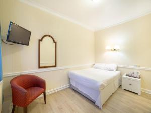 a bedroom with a bed and a chair and a mirror at George Hotel, Burslem, Stoke-on-Trent in Stoke on Trent