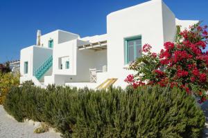 a white house with flowers in front of it at Ploes Seaside Houses in Plaka