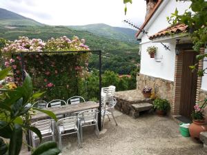 a patio with a table and chairs and flowers at Casas Rurales Carrizosa in Navaconcejo