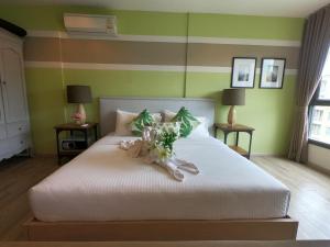 a bedroom with a white bed with flowers on it at Raincondo Ampere in Cha Am