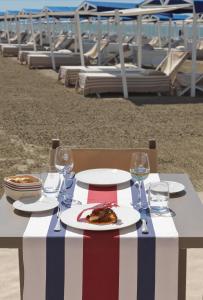 einen Tisch mit einem Teller mit Speisen und Weingläsern in der Unterkunft Augustus Hotel & Resort in Forte dei Marmi
