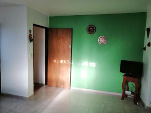 a room with a green wall with a door and a television at Luminoso Departamento Mendoza in Mendoza
