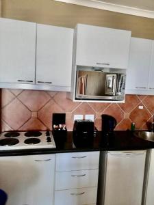 a kitchen with a stove top oven and a microwave at Cape Town Beachfront Apartments at Leisure Bay in Cape Town
