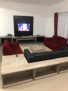 ein Wohnzimmer mit einem Sofa und einem TV in der Unterkunft casa de praia com piscina e hidromassagem in Arraial do Cabo