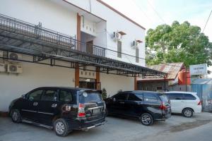dwa samochody zaparkowane na parkingu obok budynku w obiekcie RedDoorz near Pasar Baru Mamuju w mieście Mamuju