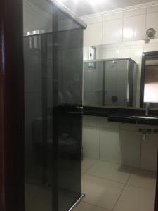 a bathroom with a glass door with a sink and a mirror at Hotel Solar Flores in Alegrete