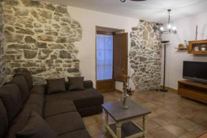 Una sala de estar con un sofá y una pared de piedra. en Alojamiento Rural URGAIN I y II, en Lekunberri