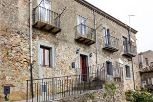 een oud stenen gebouw met balkons en een rode deur bij Casa vacanze Ai Valàti CIR 19082-037C20-6280 in Geraci Siculo