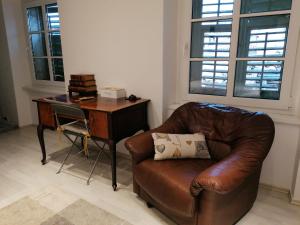 a brown leather couch sitting in a room with a desk at Via Corso in Rijeka