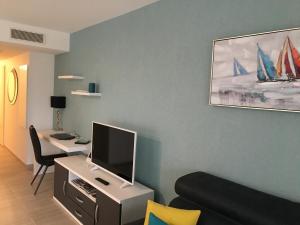 a living room with a tv and a desk with a couch at O FIL DE L'EAU BANDOL - App A05 - T3 avec Jardin et terrasse in Bandol