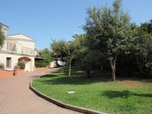 Une passerelle en briques avec des arbres dans une cour dans l'établissement Borgo Saraceno Mirto 5, à San Pasquale