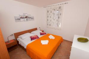 a bedroom with a bed with an orange blanket at Melada in Molat