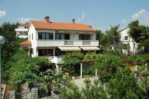 a large white house on a hill with trees at Apartments Jurina in Krk