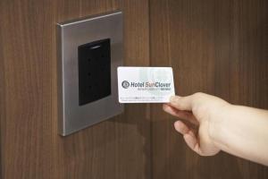 a person holding a card in front of a door at Hotel Sun Clover Koshigaya Station - Vacation STAY 55382 in Koshigaya