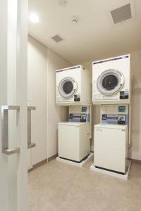 uma lavandaria com duas máquinas de lavar roupa e uma máquina de lavar e secar roupa em Hotel Sun Clover Koshigaya Station - Vacation STAY 55372 em Koshigaya