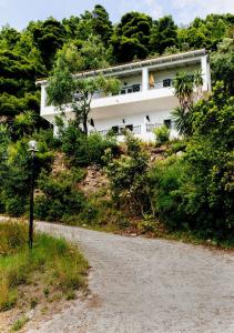 a white house on a hill with a gravel road at Yaliskari Beach in Pelekas