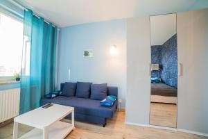 a living room with a blue couch and a bed at Apart Harmony - Apartamenty Nexo in Puck
