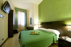 una camera d'albergo con letto verde e vassoio di frutta di Hotel Ideale a Milano