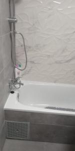 Apartment Grand Via في أليكانتي: حوض استحمام أبيض مع رأس دش في الحمام