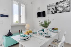 una sala da pranzo con tavolo bianco e piatti blu e bianchi di MILLEBOLLEBLU APARTMENTS a Lido Marini