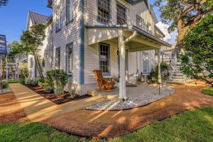 a white house with a porch with a wooden chair at McKenize Guest House: Inks Suite 1 BD, 1BA in Marble Falls