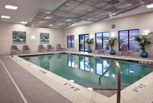 a large swimming pool in a building with tables and chairs at Furnished Quarters at 15/25 Bank Street in White Plains