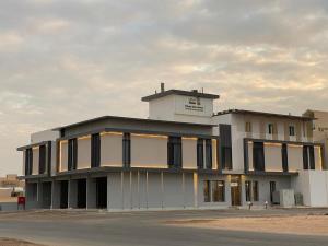 ein großes weißes Gebäude mit schwarzen Fenstern auf einer Straße in der Unterkunft Sadan Furnished Apartments in Riad