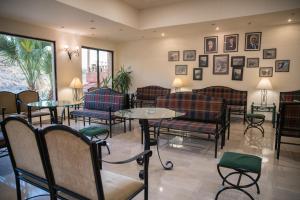 una sala de espera con mesas, sillas y cuadros en la pared en Petra Palace Hotel en Wadi Musa
