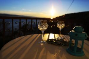 two wine glasses on a table with the sunset in the background at Apartments STANIĆ - apartments with a view of the sea and sandy beach in Duće