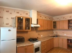 a kitchen with wooden cabinets and a white refrigerator at Двухкомнатные апартаменты в центре города Карла Маркса 163 in Tambov