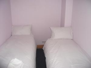 two beds in a small room with white sheets and pillows at Bryn Cottage in Llandderfel