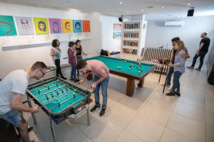 a group of people standing around a pool table at America Del Sur Hostel Buenos Aires in Buenos Aires